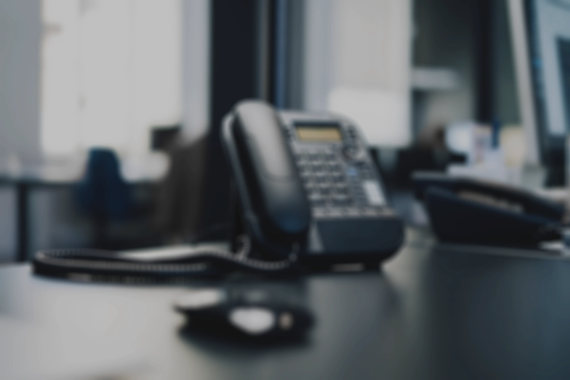 A blurry image of a desk with a phone and other office equipment.