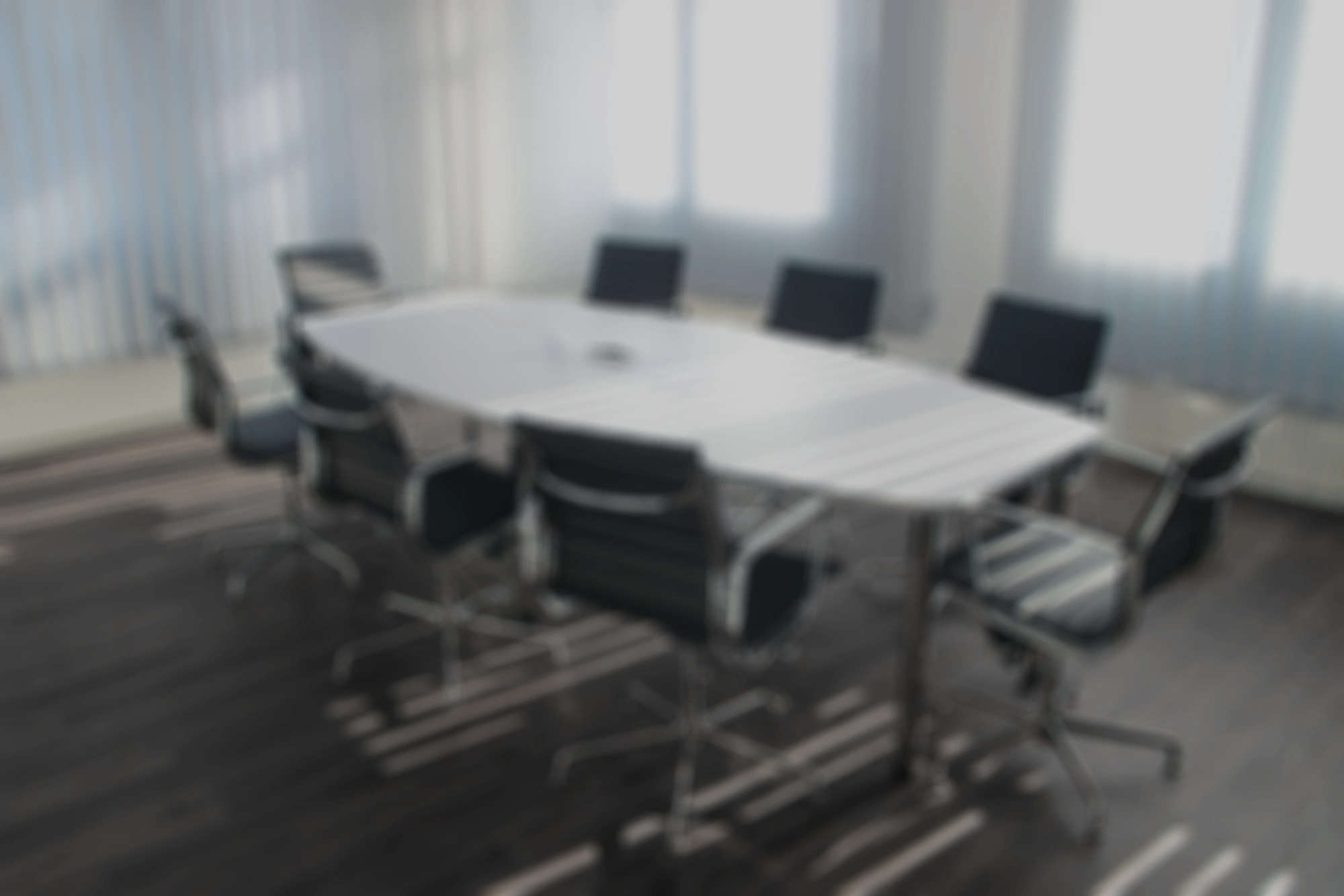 A blurred image of a conference room with a large table and chairs.